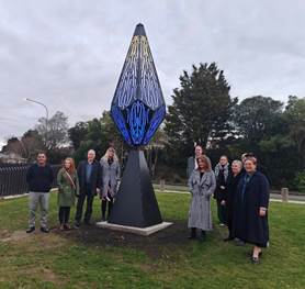 A group of people standing in front of a sculpture

Description automatically generated